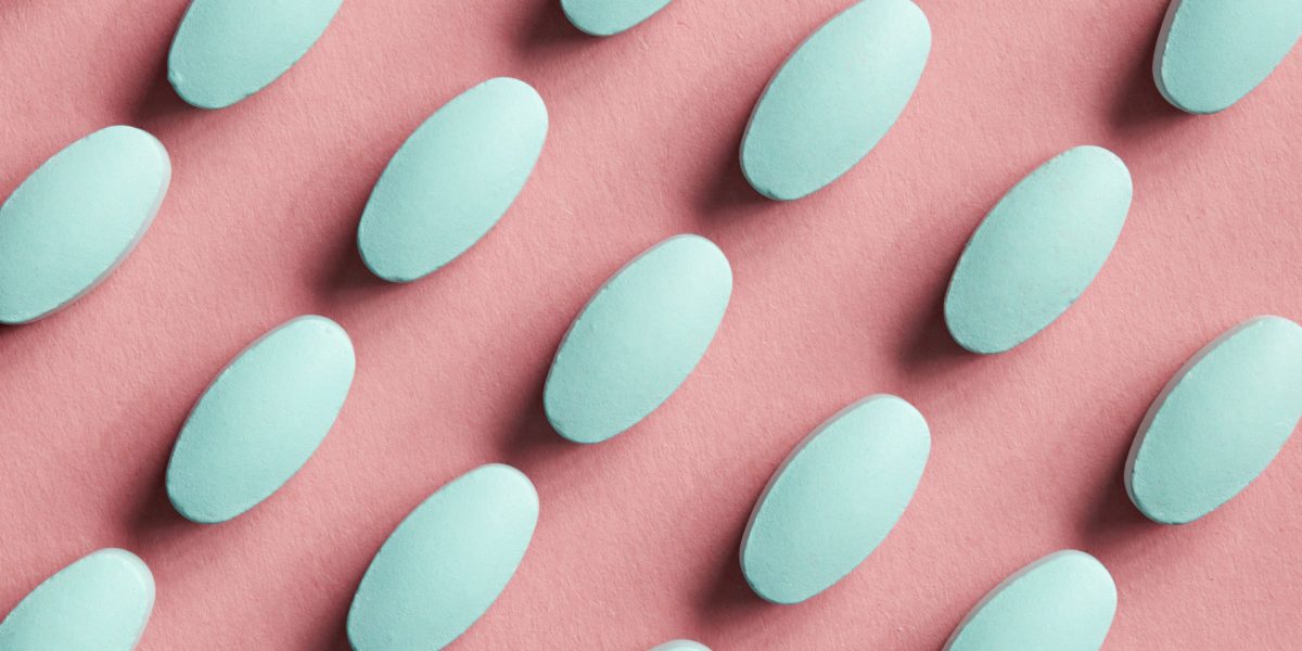 green pills on pink background, top view
